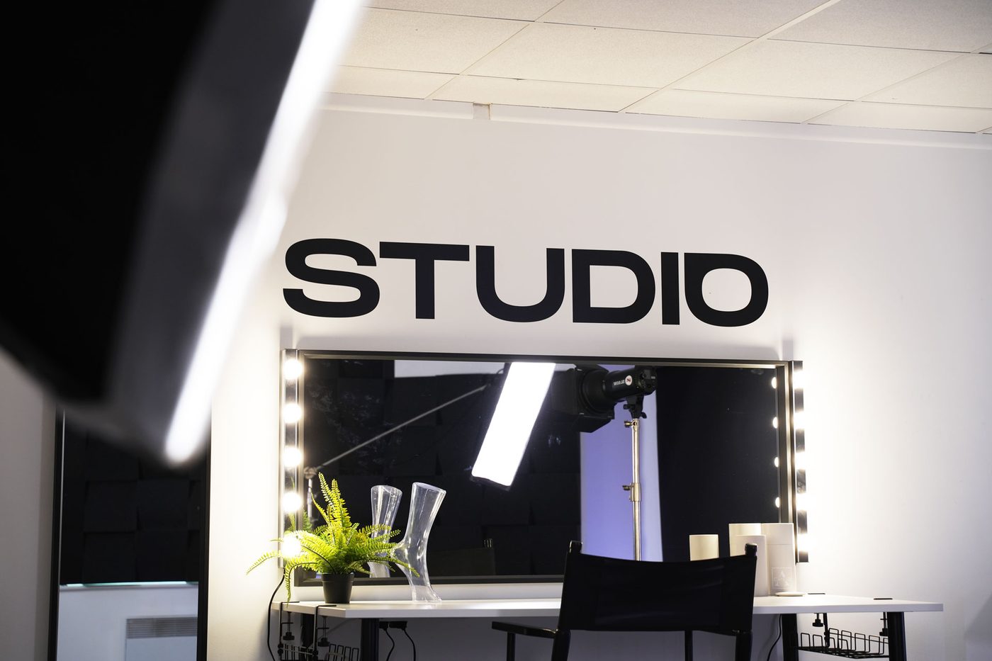 The Studio wall sign above the lit mirror