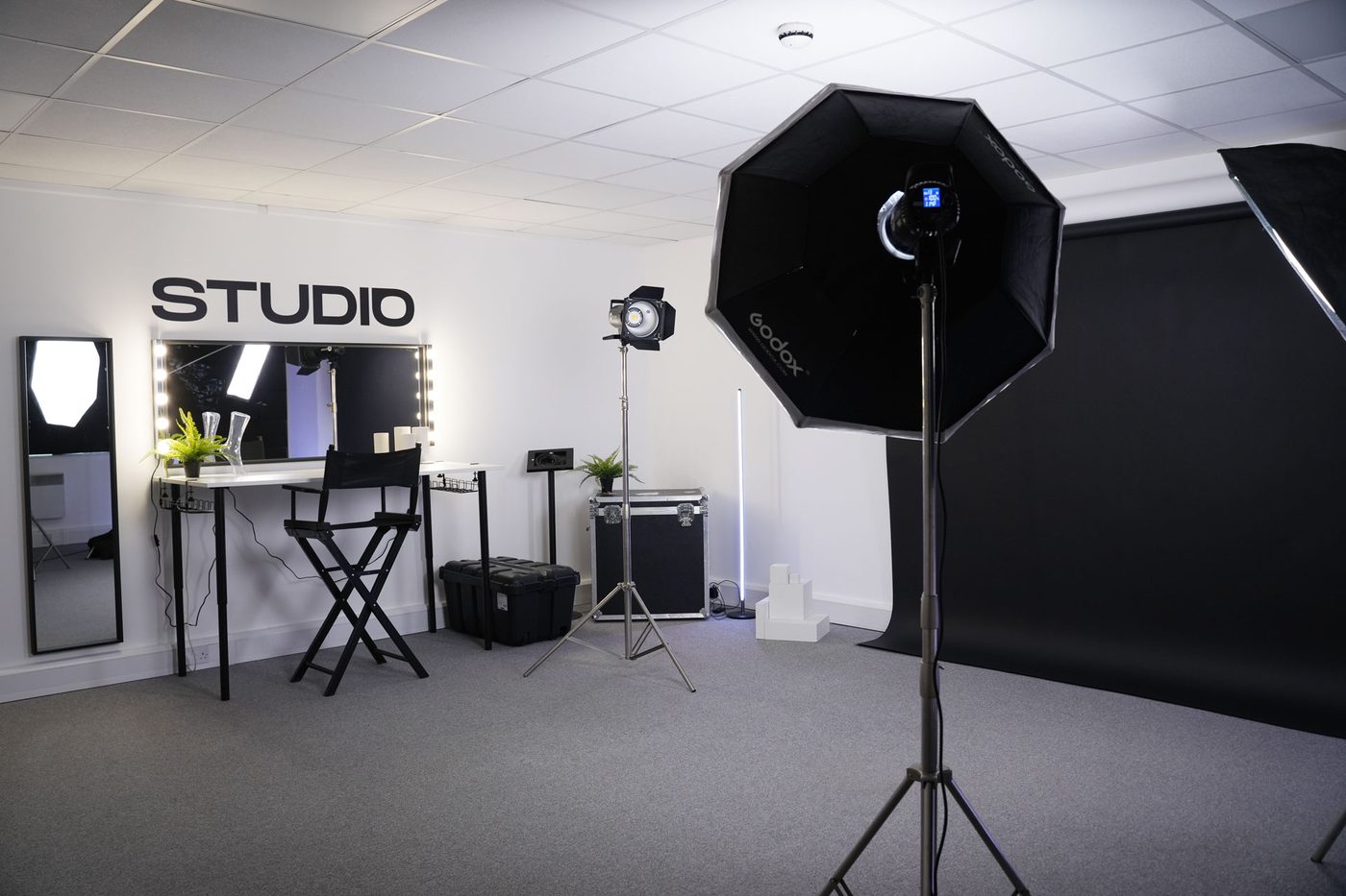 The Stud1o space: beauty station under the Studio wall sign, light stands and a black paper backdrop